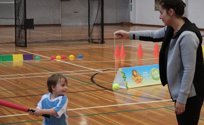 child playing t-ball with mum